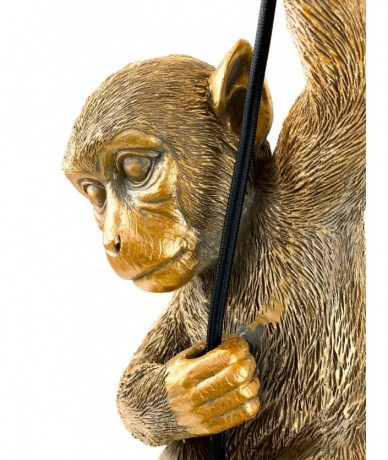 Mennyezeti lámpazsinóron hintázó arany majom lámpadekoráció, a zsinór és a foglalat fekete