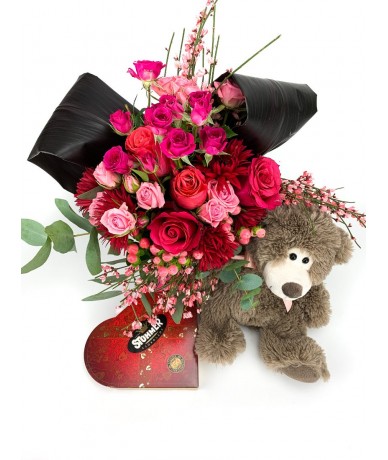 Teddy bear with a truly romantic bouquet of red-pink flowers, chocolate and teddy bear