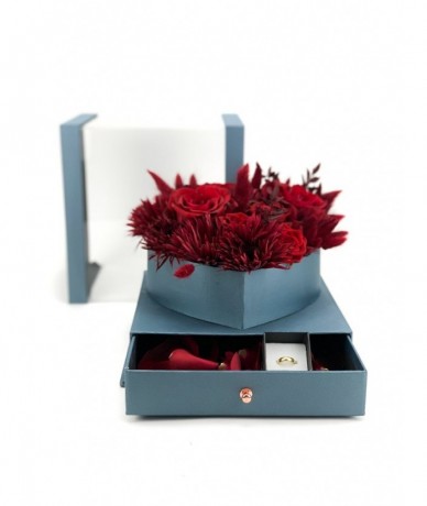 Virágdoboz vörös virágokból elegáns kék dobozban, szirmokkal teli fiókkal, szalaggal átkötve