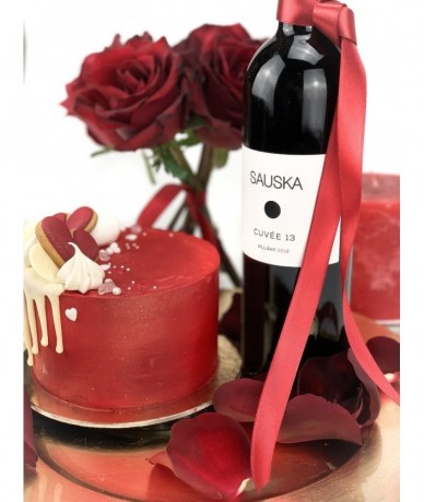 Arany tálcán kis rózsacsokor, egy üveg vörösbor, egy minitorta és egy gyertya szirmokkal