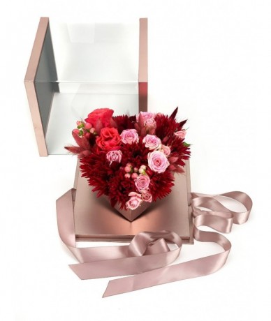Rozé színű átlátszó fedelű dobozban romantikus oink-vörös virágok szív formában, szalaggal átkötve